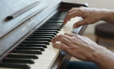 Les mains d'une personne mûre en apprentissage sur un clavier de piano, geste hésitant