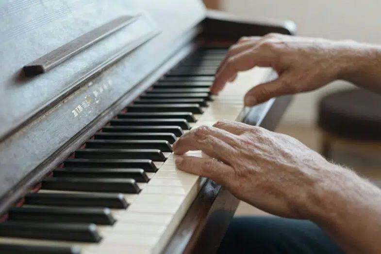Les mains d'une personne mûre en apprentissage sur un clavier de piano, geste hésitant