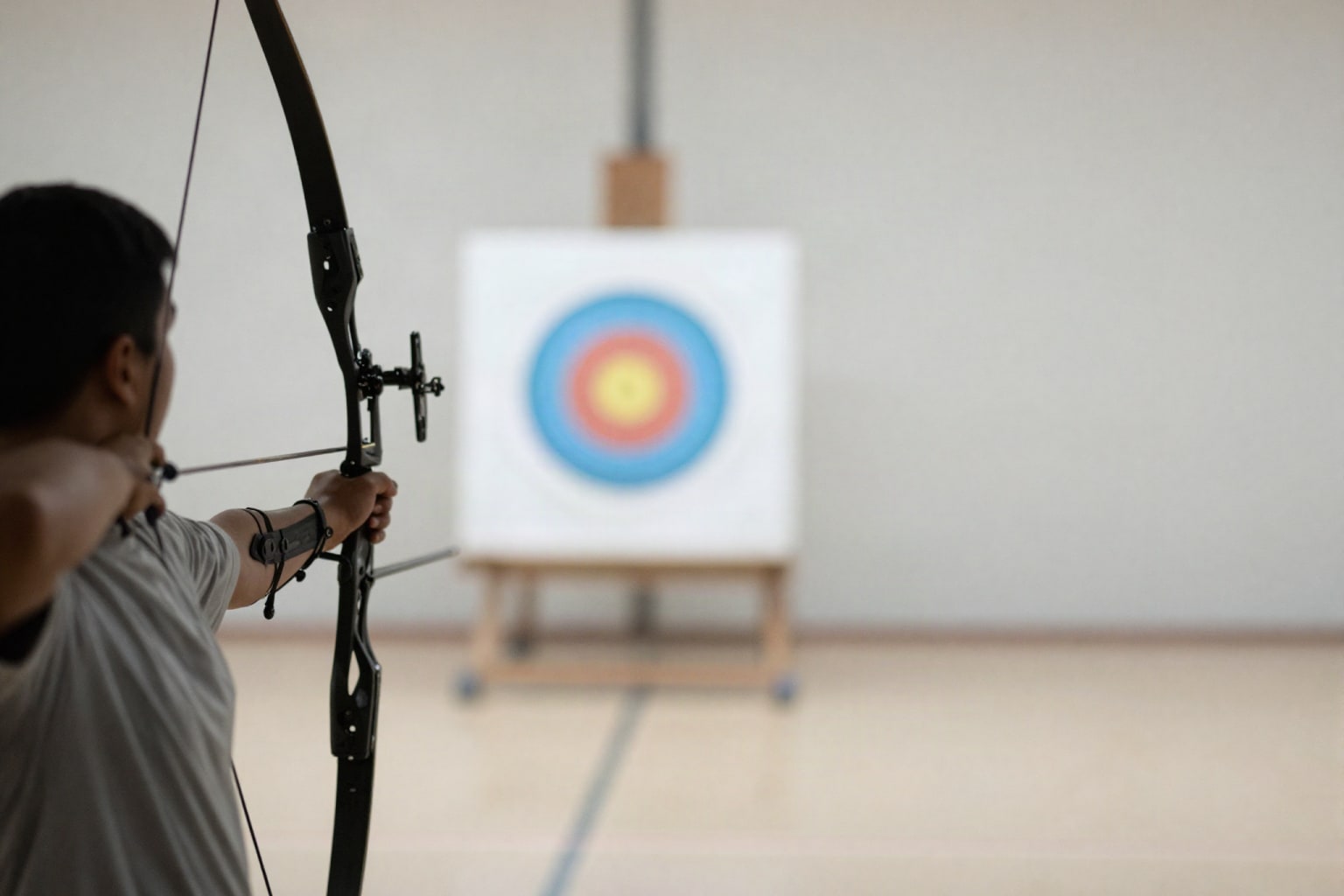 Un archer de dos, arc tendu, silhouette en contre-jour dans une salle claire